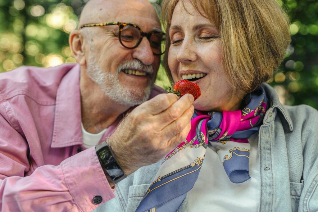 older man feeing older woman a strawberry